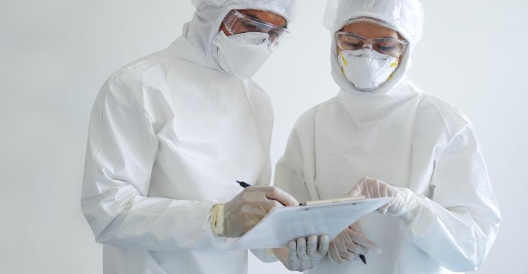 two-healthcare-workers-in-hazmat-suits-examine-clipboard.jpg